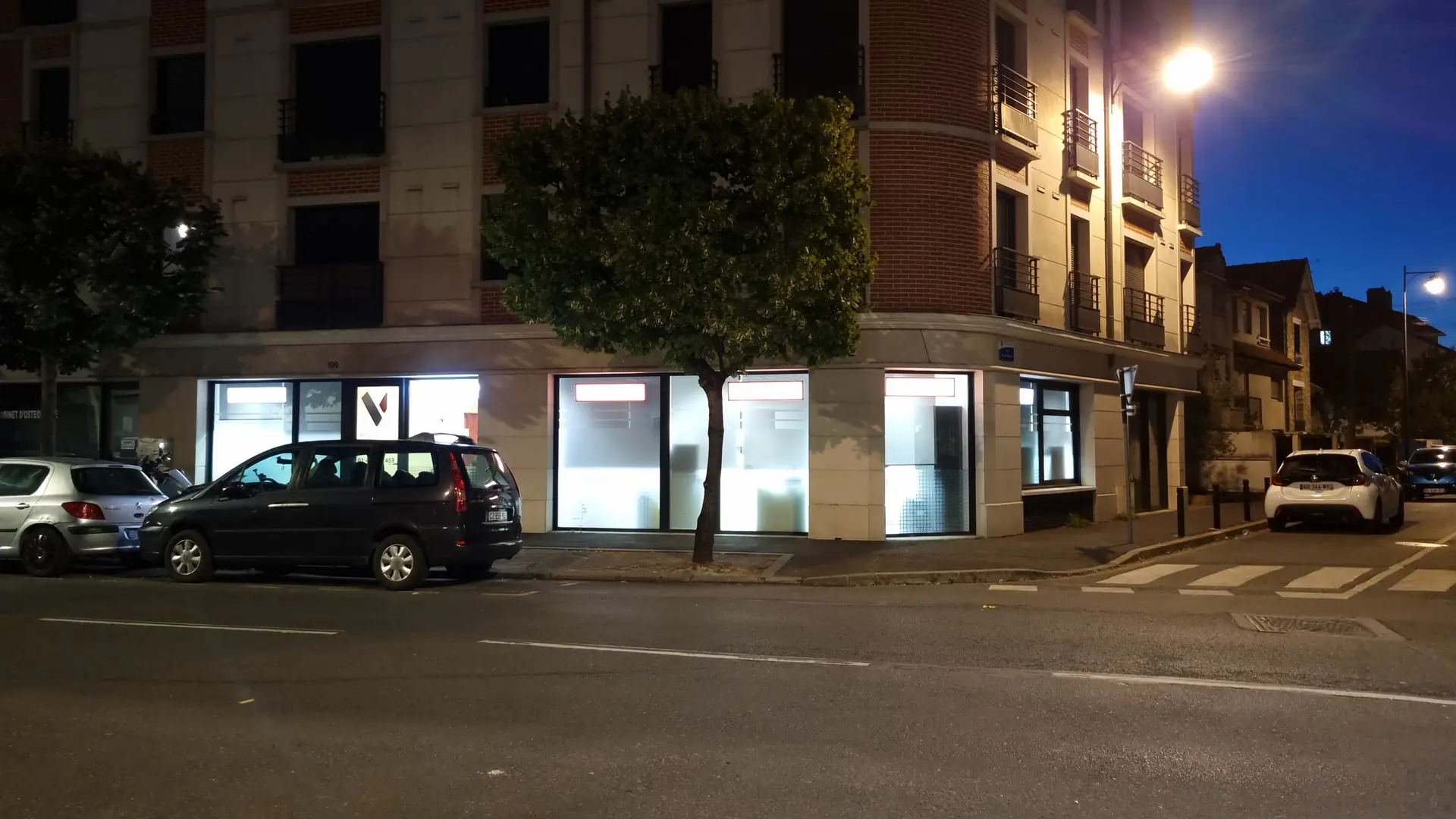 Vue d'angle de rue, façade de la clinique éclairée de nuit