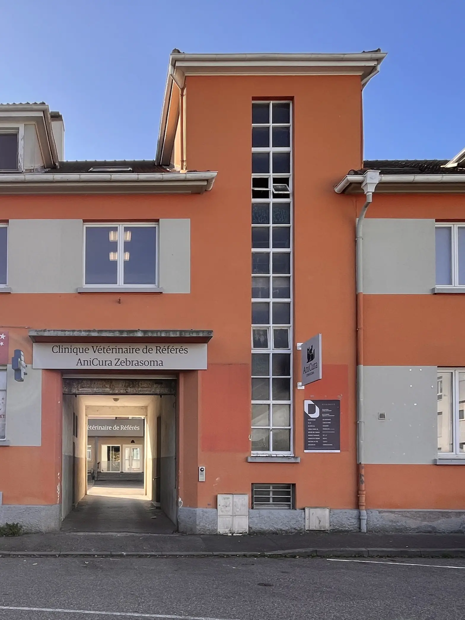 Façade avant d'une clinique vétérinaire à Strasbourg avec un grand porche et des fenêtres orange et grises.