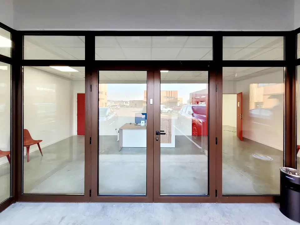 Façade vitrée extérieure en aluminium marron et verre transparent d'une clinique vétérinaire sous un auvent, sol en béton.